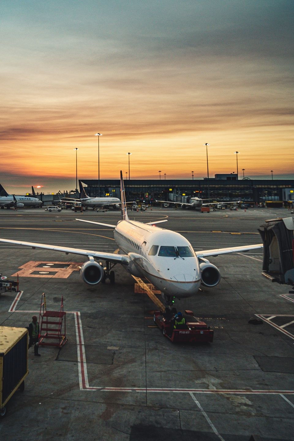 Aircraft at the gate at sunset with cargo handling equipment on the apron
